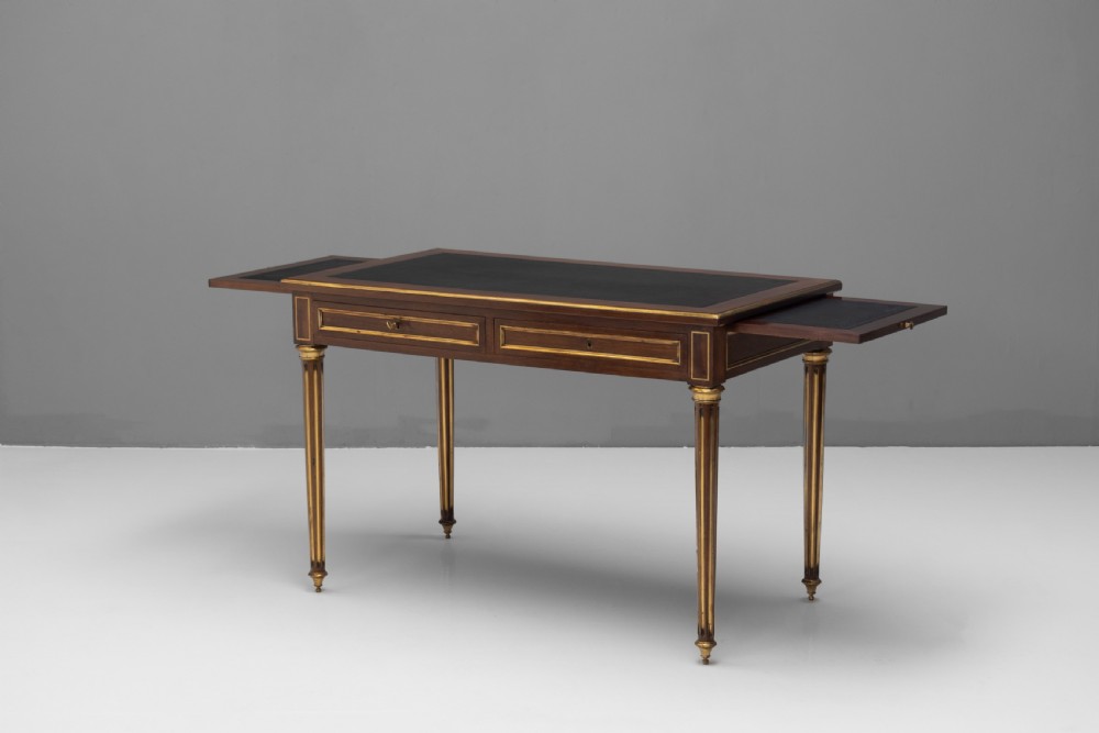 A French Louis XVI style mahogany bureau plat featuring a dark leather writing insert, gilt-bronze trim, frieze drawers, and fluted tapered legs. View II
