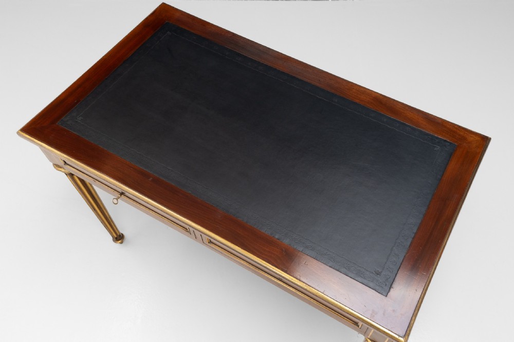 A French Louis XVI style mahogany bureau plat featuring a dark leather writing insert, gilt-bronze trim, frieze drawers, and fluted tapered legs. View VI