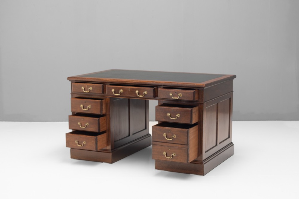 An antique mahogany pedestal desk featuring a dark leather top, fluted side columns, nine drawers with brass handles, and a central kneehole. View II
