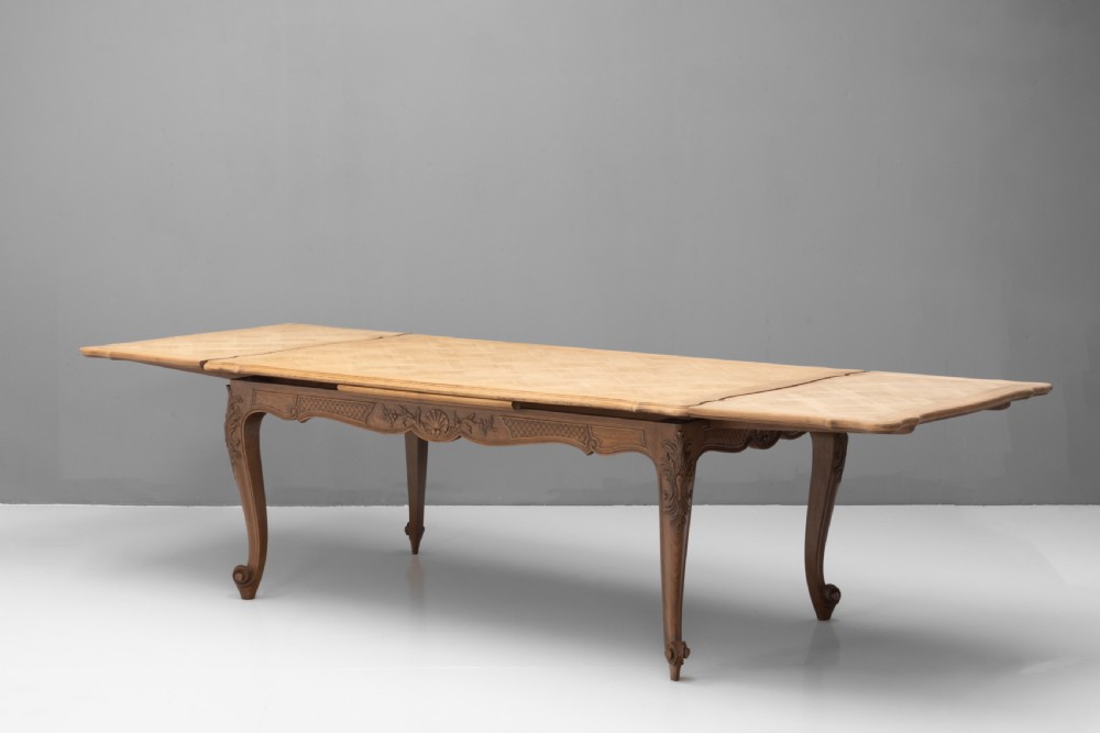 An extendable French Provincial oak dining table with a parquet top, carved shell apron, and cabriole legs ending in scroll feet. View IV