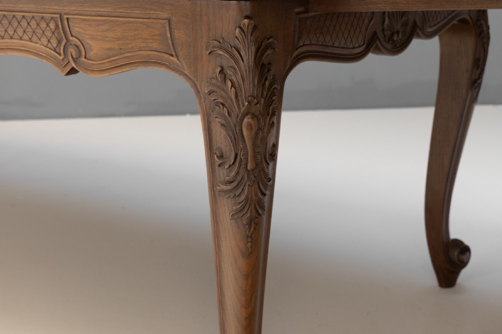 An extendable French Provincial oak dining table with a parquet top, carved shell apron, and cabriole legs ending in scroll feet. View VII