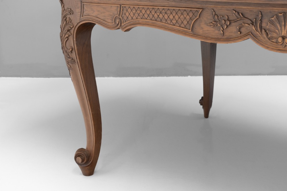 An extendable French Provincial oak dining table with a parquet top, carved shell apron, and cabriole legs ending in scroll feet. View X