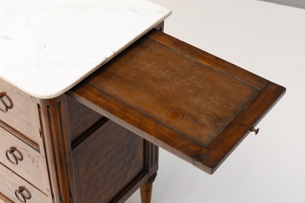 A Neoclassical style three-drawer wooden chest featuring geometric parquetry inlay, brass ring handles, tapered legs, and a white marble top surface. View VIII