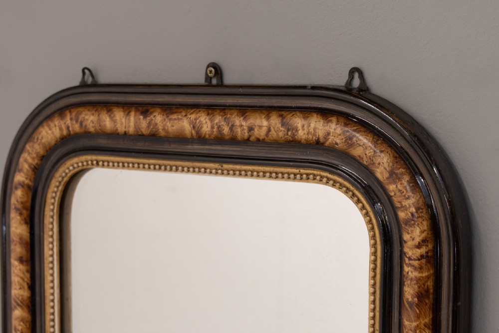 A small Louis Philippe wall mirror featuring rounded upper corners, an ebonised outer profile, figured wood veneer, and a beaded gilt inner border. View III
