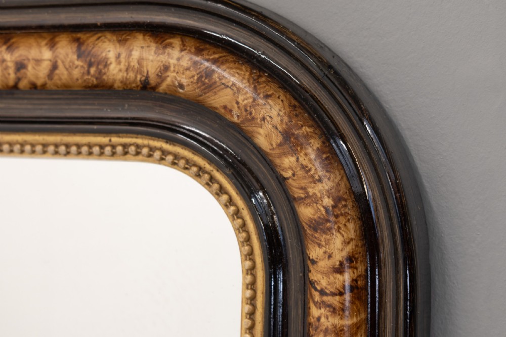 A small Louis Philippe wall mirror featuring rounded upper corners, an ebonised outer profile, figured wood veneer, and a beaded gilt inner border. View IV