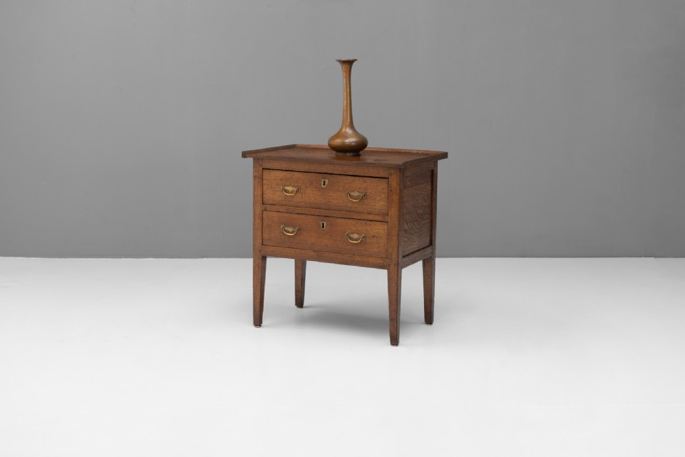 A Georgian oak two-drawer chest featuring brass drop handles, keyhole escutcheons, and square tapered legs against a neutral background. View III