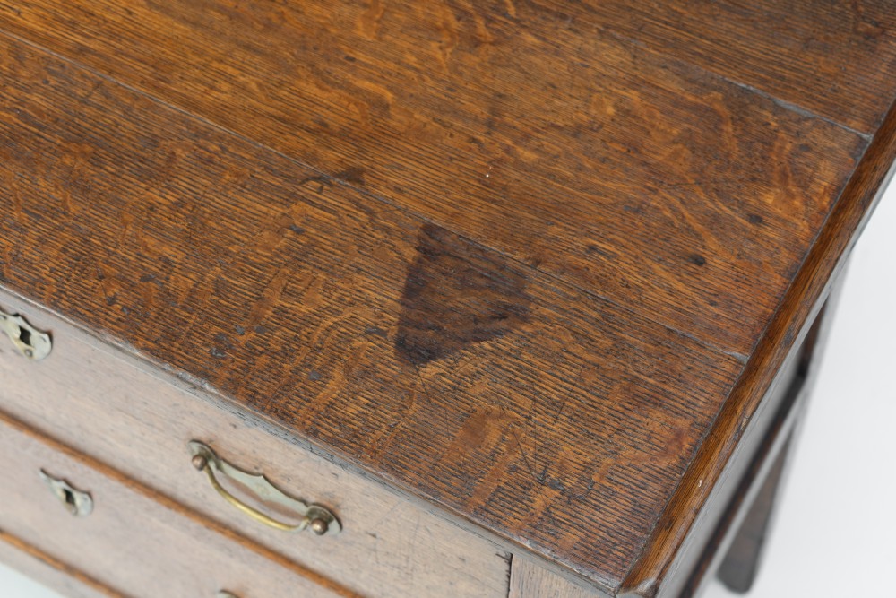 A Georgian oak two-drawer chest featuring brass drop handles, keyhole escutcheons, and square tapered legs against a neutral background. View V