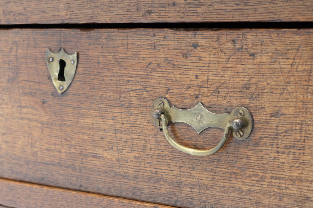 A Georgian oak two-drawer chest featuring brass drop handles, keyhole escutcheons, and square tapered legs against a neutral background. View VI