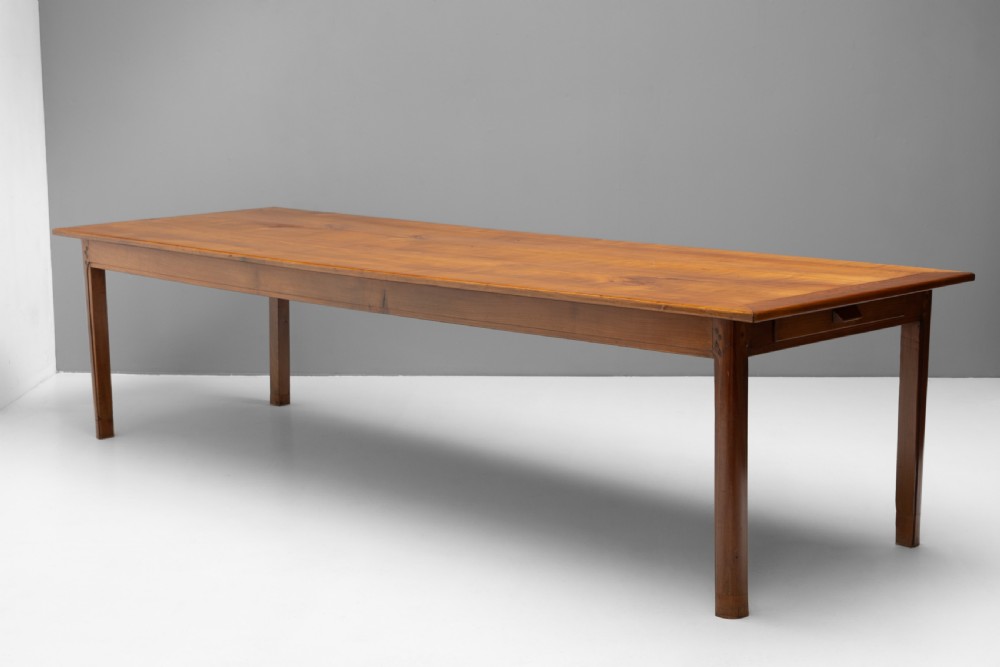 A long rectangular antique cherry wood farm table featuring straight legs and a smooth polished finish.