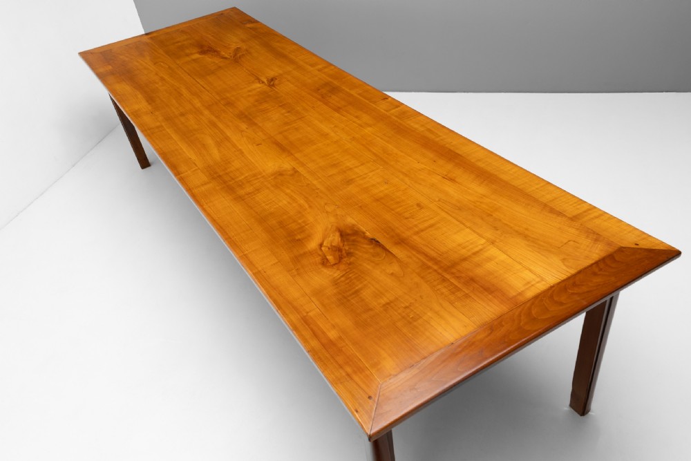 A long rectangular antique cherry wood farm table featuring straight legs and a smooth polished finish. View IV