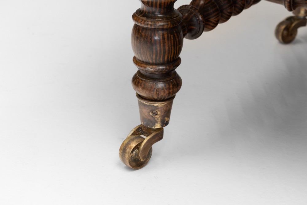 A 19th-century French bobbin-turned oak settee featuring a high upholstered back panel, spool-turned wooden framing, and brass castors. View VII