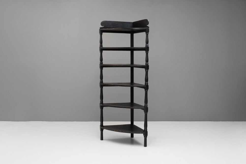 A tall 19th-century ebonised wooden corner shelf unit featuring six tiered triangular shelves and turned spindle supports.