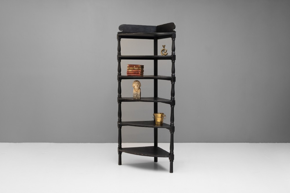 A tall 19th-century ebonised wooden corner shelf unit featuring six tiered triangular shelves and turned spindle supports. View II