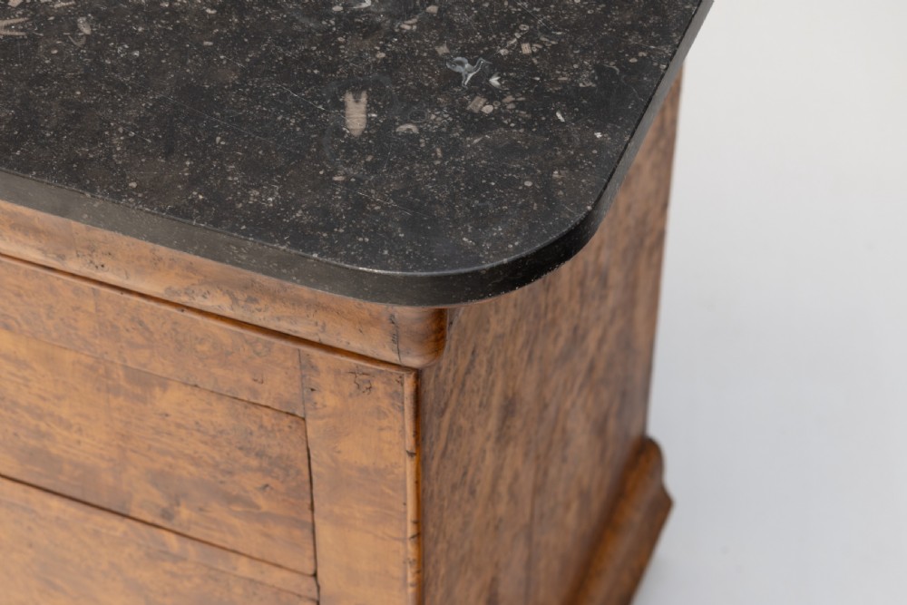 A 19th-century elm commode chest of drawers featuring a dark marble top, three full-width drawers with oval brass escutcheons, and a prominent figured wood grain. View V