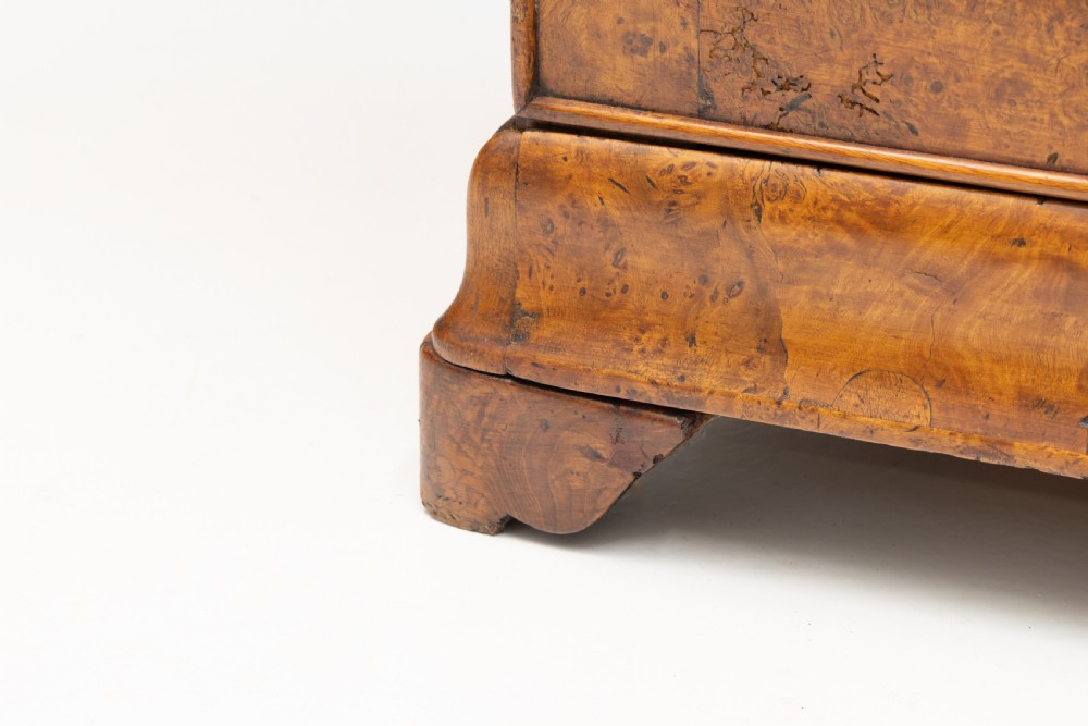 A 19th-century elm commode chest of drawers featuring a dark marble top, three full-width drawers with oval brass escutcheons, and a prominent figured wood grain. View VI