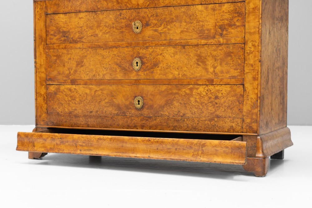 A 19th-century elm commode chest of drawers featuring a dark marble top, three full-width drawers with oval brass escutcheons, and a prominent figured wood grain. View VII