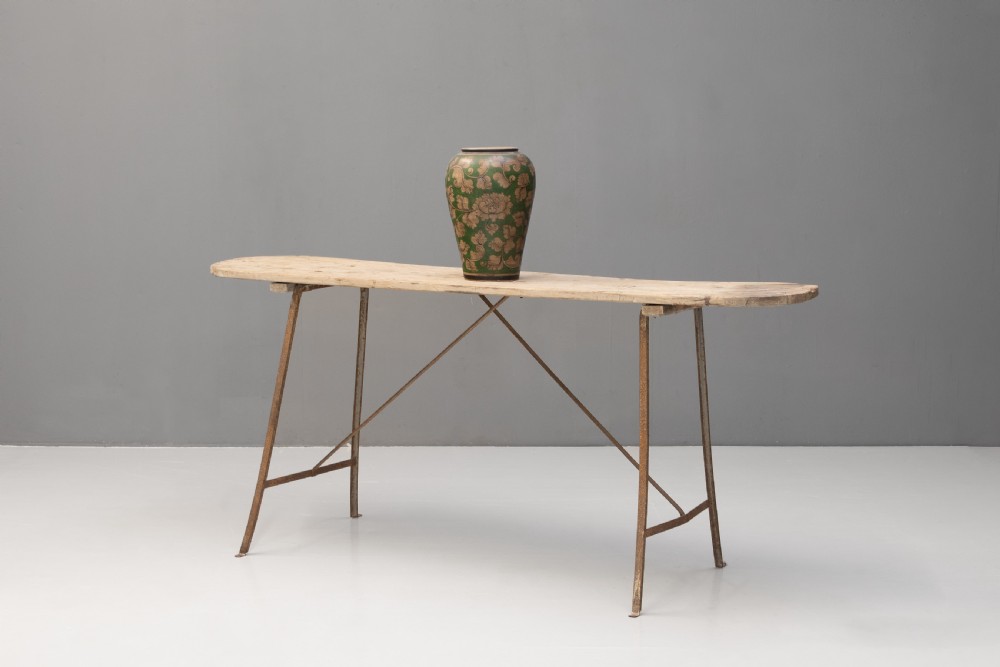 A long narrow rustic table featuring a natural pale wood top with rounded ends supported by slender brown metal legs with diagonal cross-bracing. View III
