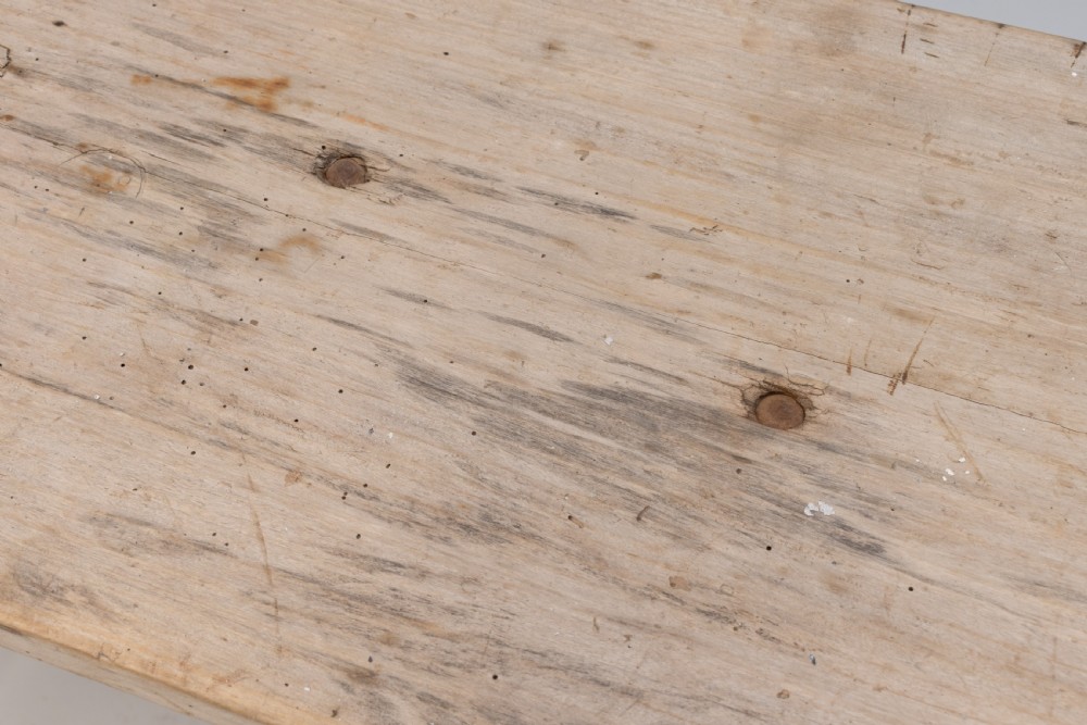 A long narrow rustic table featuring a natural pale wood top with rounded ends supported by slender brown metal legs with diagonal cross-bracing. View VII