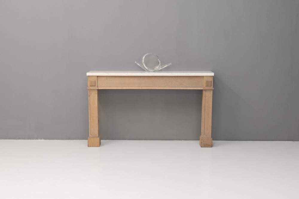 A light oak console table featuring rectangular pilaster legs on plinths and a thick rectangular white marble top set against a neutral grey wall. View III