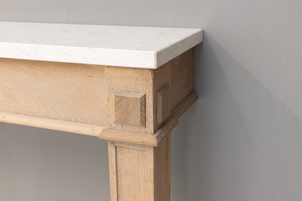 A light oak console table featuring rectangular pilaster legs on plinths and a thick rectangular white marble top set against a neutral grey wall. View V