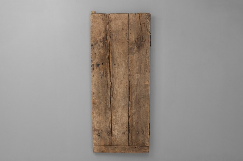 A tall weathered antique oak plank door featuring vertical wooden boards joined with visible iron studs and a natural aged patina. View II