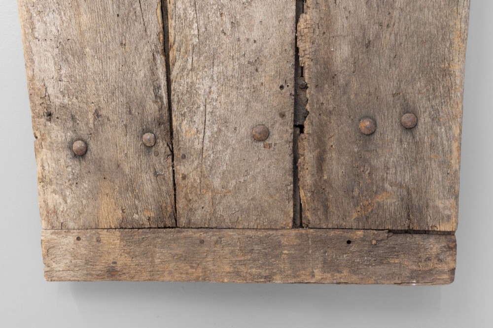 A tall weathered antique oak plank door featuring vertical wooden boards joined with visible iron studs and a natural aged patina. View VI