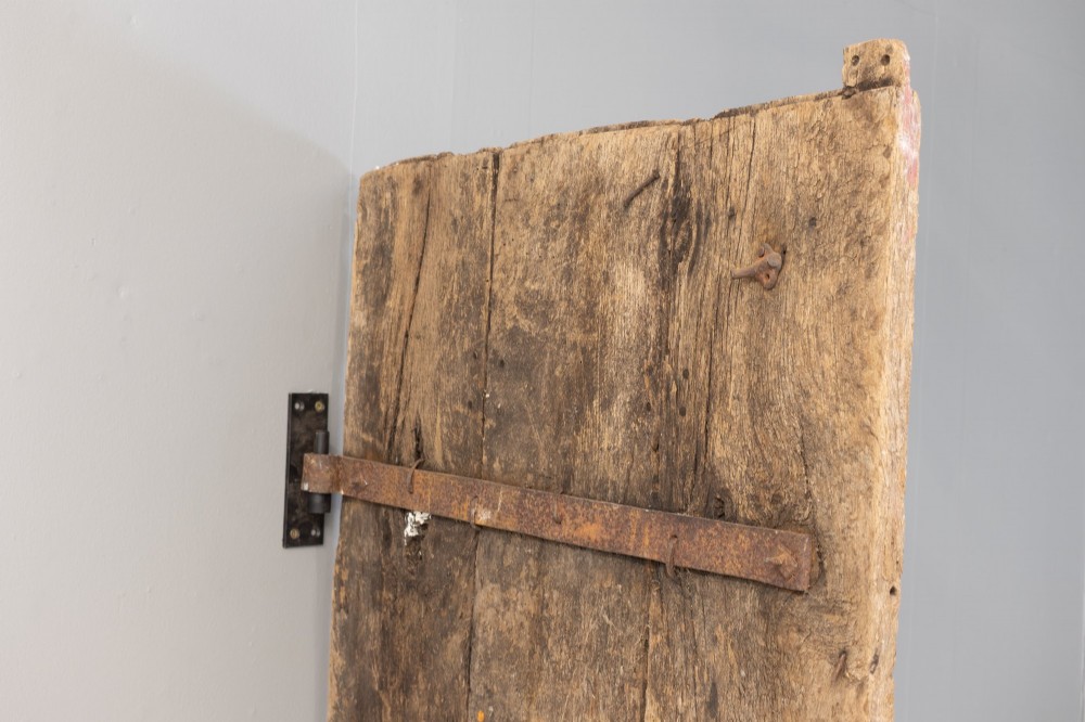 A tall weathered antique oak plank door featuring vertical wooden boards joined with visible iron studs and a natural aged patina. View VII