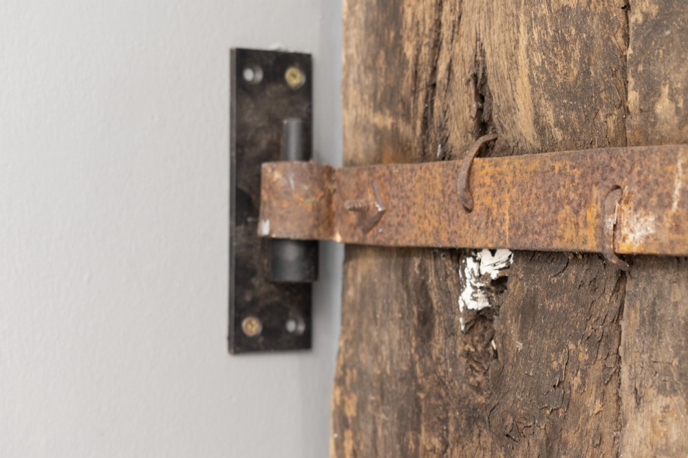 A tall weathered antique oak plank door featuring vertical wooden boards joined with visible iron studs and a natural aged patina. View VIII
