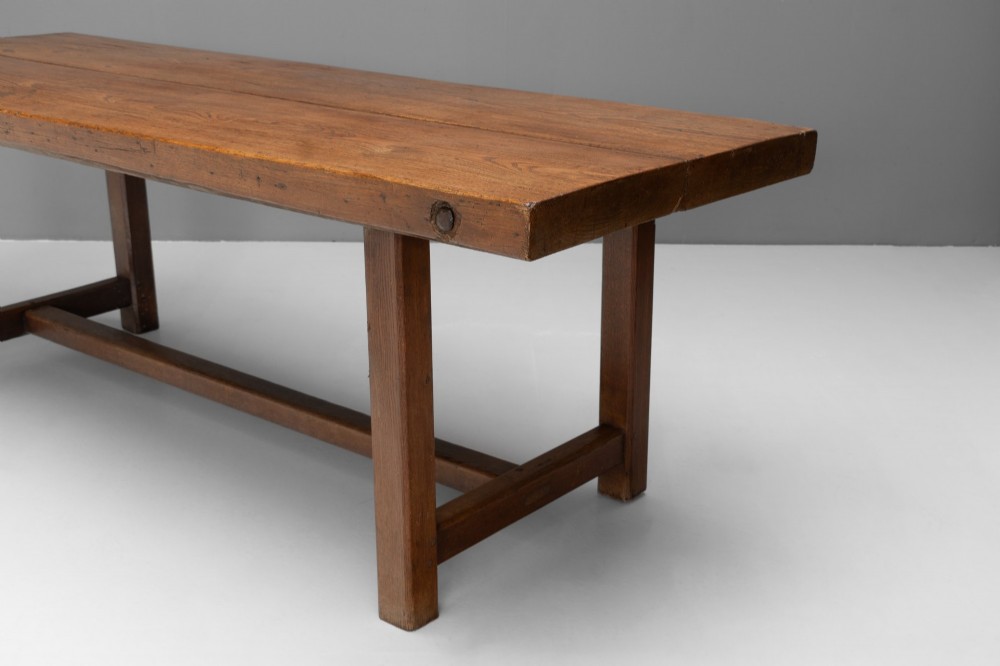 A long rustic wooden farmhouse dining table with a thick plank top, square legs, and an H-stretcher base. View IV
