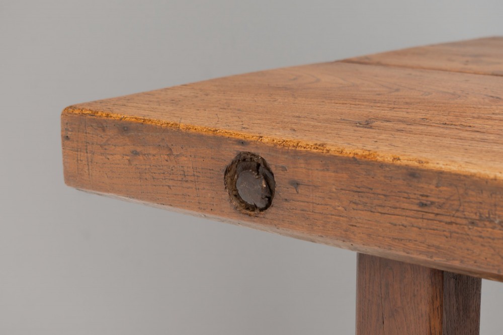 A long rustic wooden farmhouse dining table with a thick plank top, square legs, and an H-stretcher base. View V