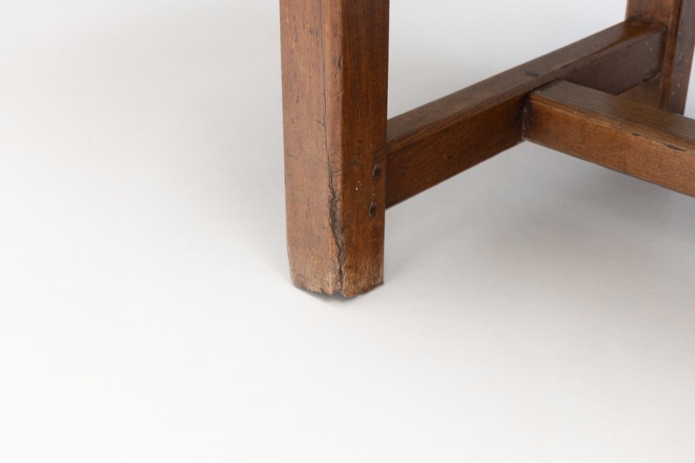 A long rustic wooden farmhouse dining table with a thick plank top, square legs, and an H-stretcher base. View VI