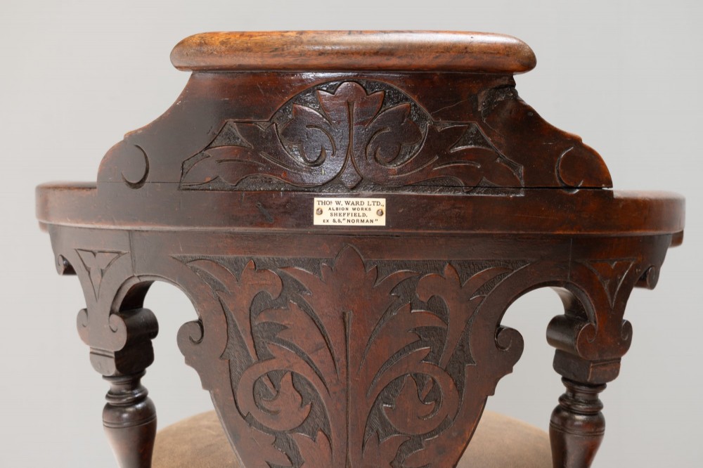 A dark brown Victorian swivel armchair featuring a carved wooden back support and a padded brown leather circular seat. View VIII
