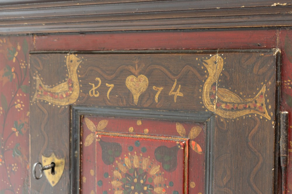 A tall, narrow folk art painted timber cupboard featuring hand-painted floral motifs, date lettering, an upper door, an open central shelf, and a lower door. View III