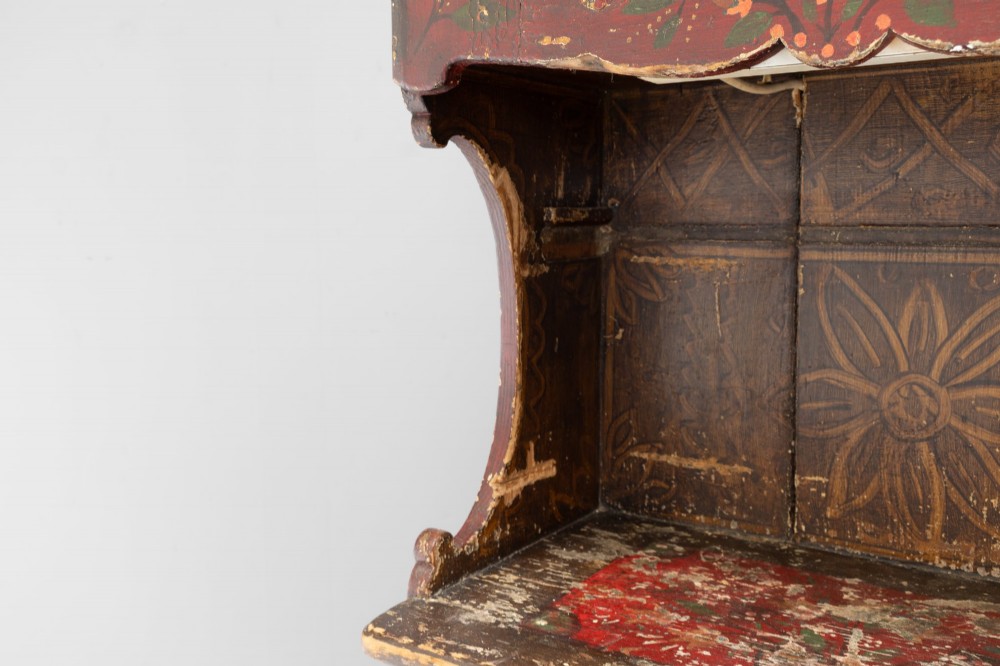 A tall, narrow folk art painted timber cupboard featuring hand-painted floral motifs, date lettering, an upper door, an open central shelf, and a lower door. View VI