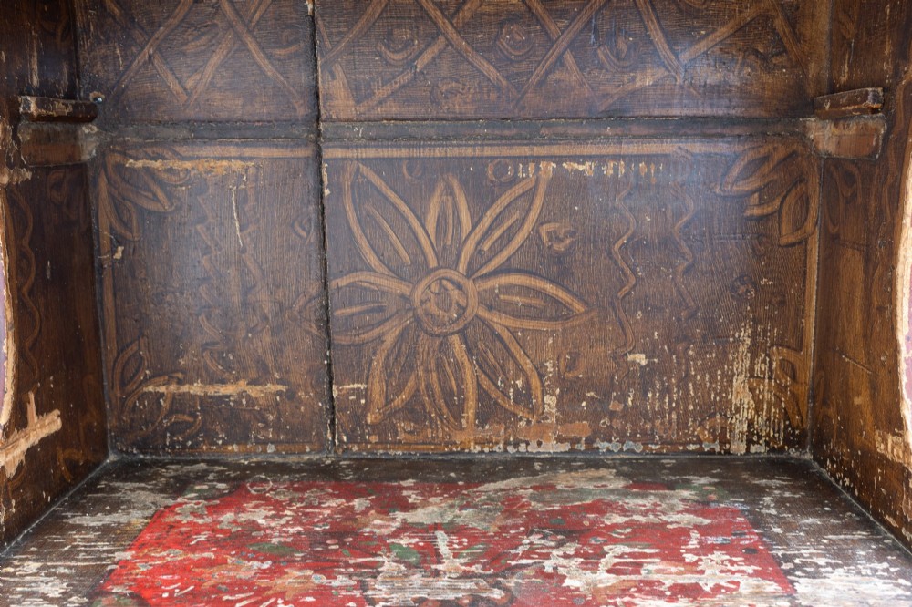 A tall, narrow folk art painted timber cupboard featuring hand-painted floral motifs, date lettering, an upper door, an open central shelf, and a lower door. View VII