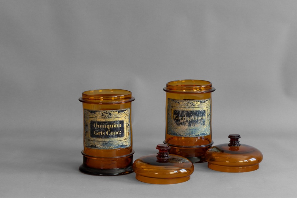 A pair of cylindrical amber glass apothecary jars with glass stoppers and original gilded French labels. View II
