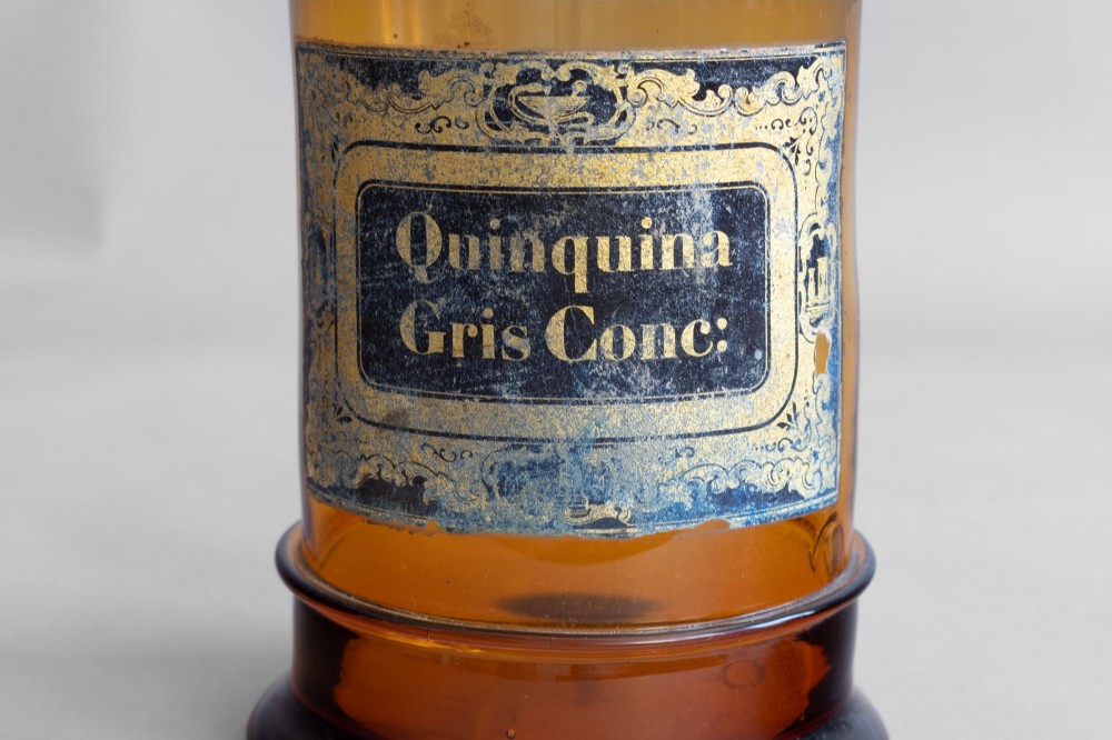 A pair of cylindrical amber glass apothecary jars with glass stoppers and original gilded French labels. View IV