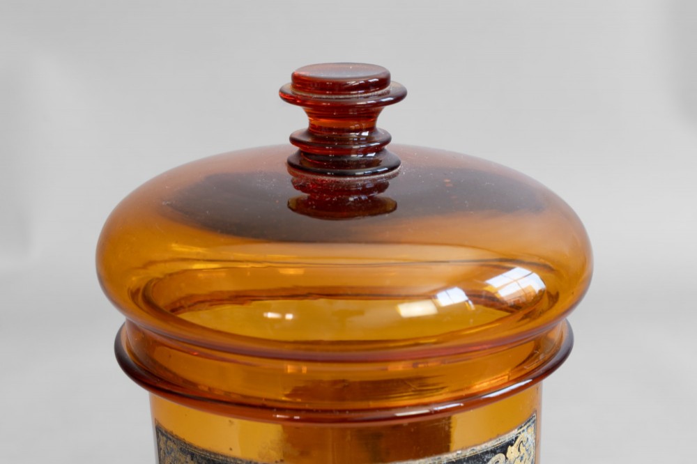 A pair of cylindrical amber glass apothecary jars with glass stoppers and original gilded French labels. View V