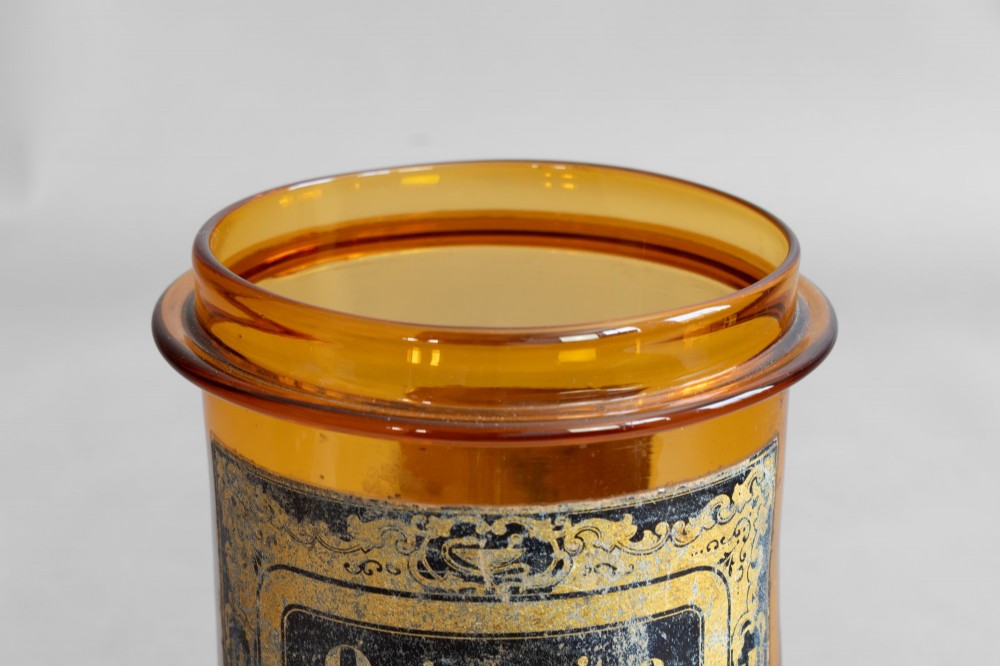A pair of cylindrical amber glass apothecary jars with glass stoppers and original gilded French labels. View VI