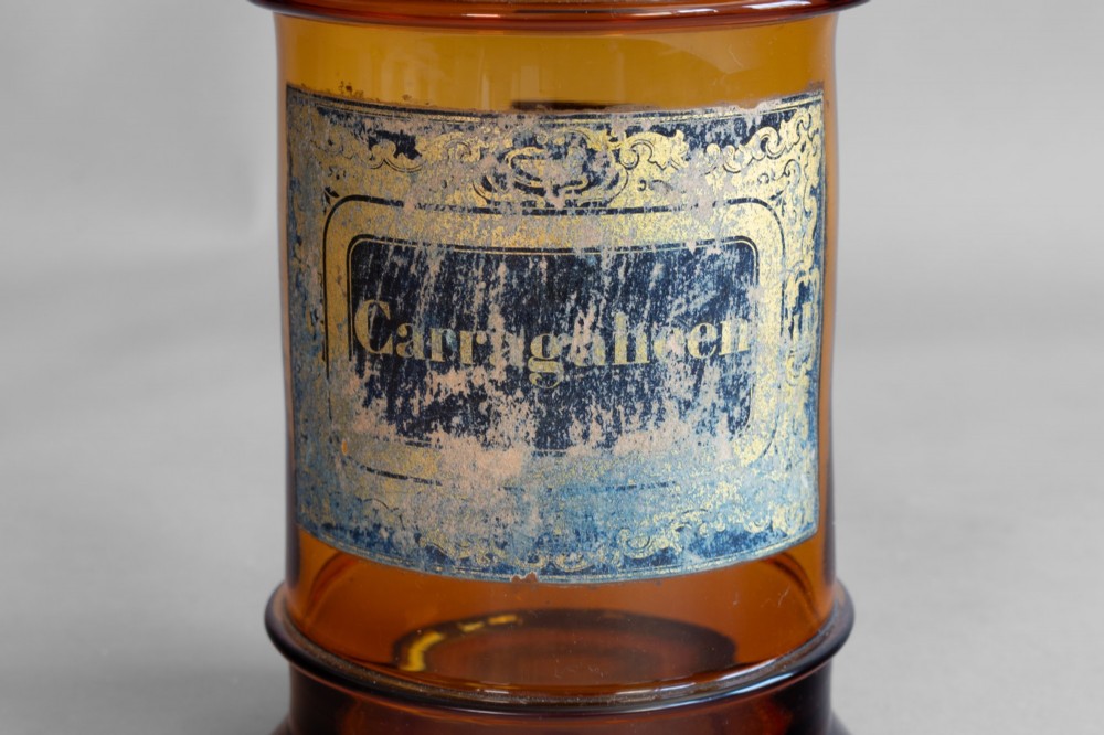 A pair of cylindrical amber glass apothecary jars with glass stoppers and original gilded French labels. View VII