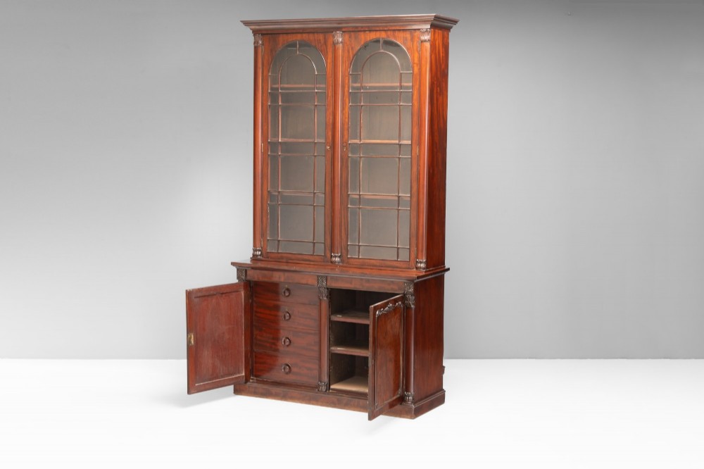 A large mahogany two-tier bookcase featuring twin upper glazed doors with arched glazing bars and a lower cupboard section with carved accents. View II