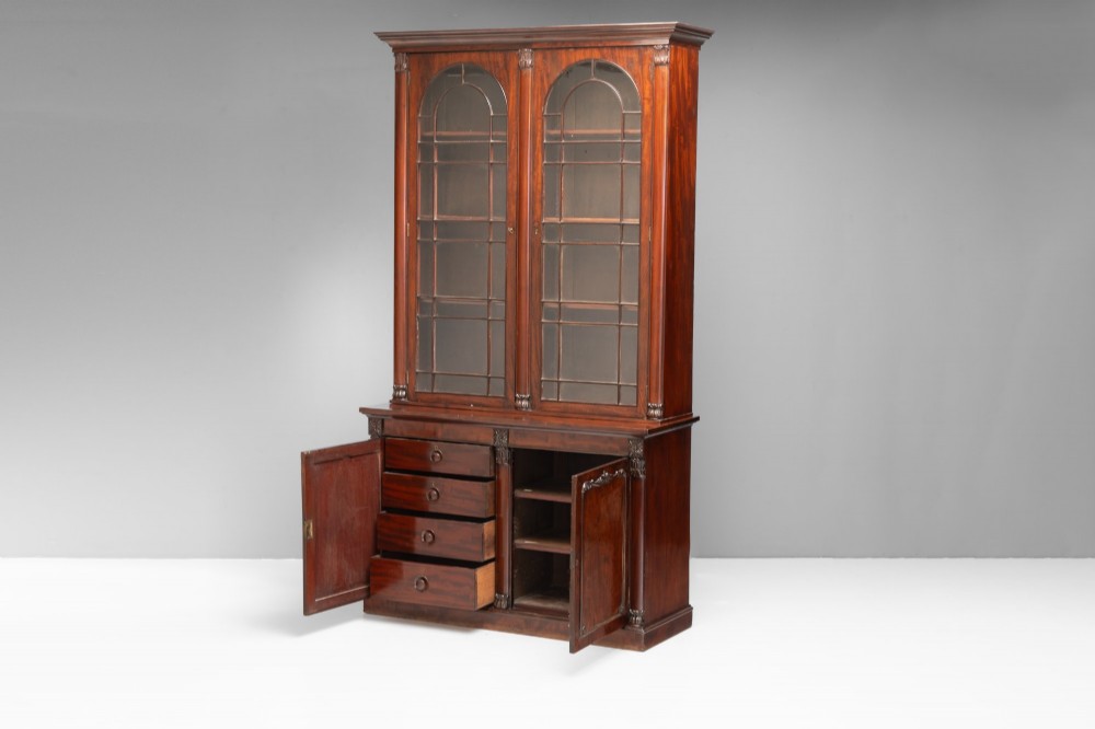 A large mahogany two-tier bookcase featuring twin upper glazed doors with arched glazing bars and a lower cupboard section with carved accents. View III