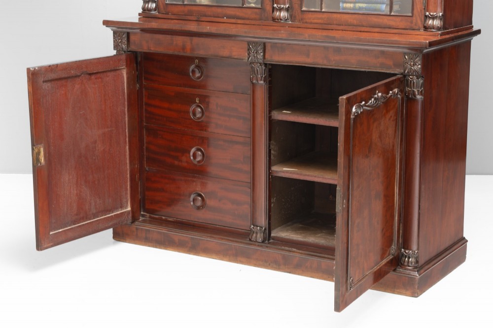 A large mahogany two-tier bookcase featuring twin upper glazed doors with arched glazing bars and a lower cupboard section with carved accents. View VI