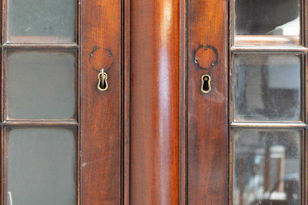 A large mahogany two-tier bookcase featuring twin upper glazed doors with arched glazing bars and a lower cupboard section with carved accents. View X