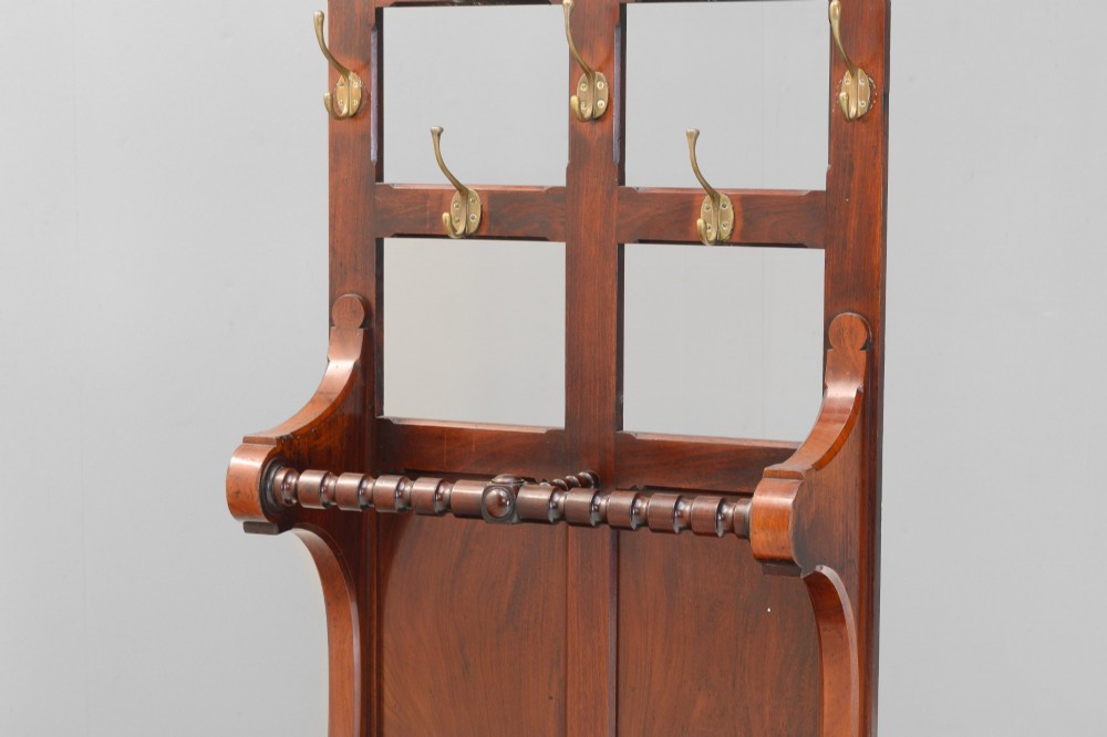A tall Victorian mahogany hallstand featuring an architectural pediment cresting, multiple brass coat hooks, and a lower stick stand with an integrated drip tray. View III