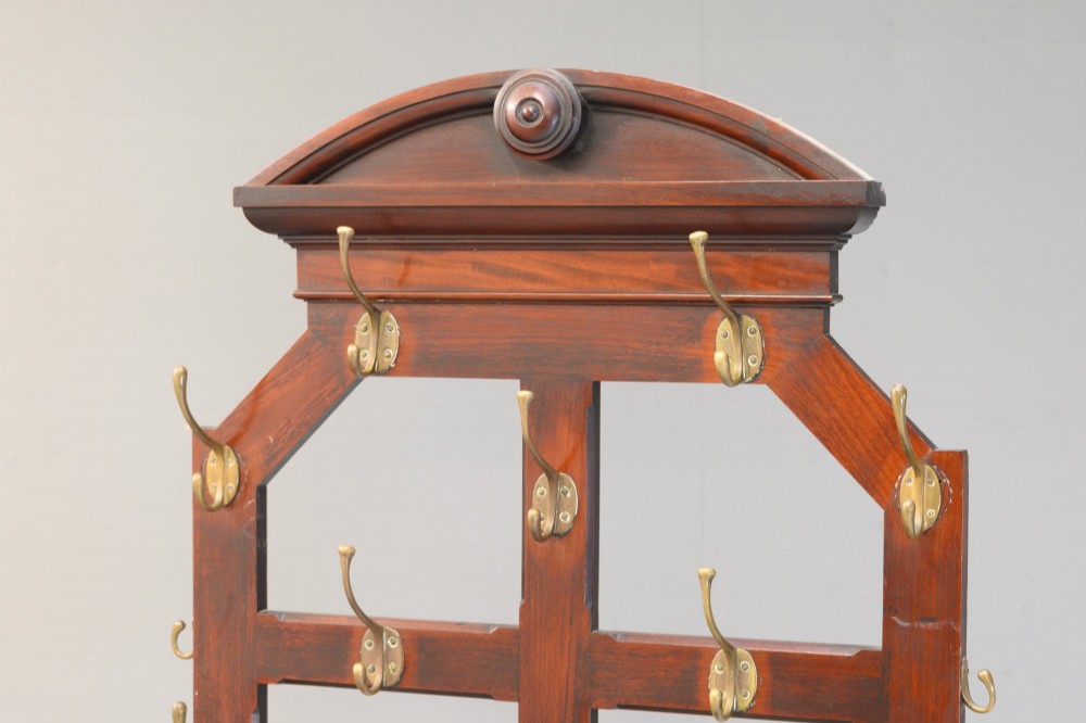 A tall Victorian mahogany hallstand featuring an architectural pediment cresting, multiple brass coat hooks, and a lower stick stand with an integrated drip tray. View IV
