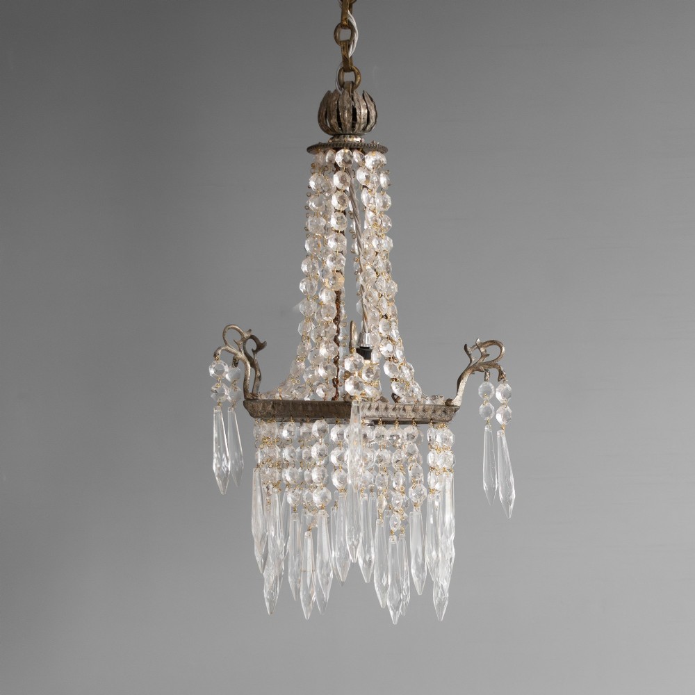 An antique French style crystal chandelier featuring tiered glass prisms, beaded crystal strands, and a decorative aged brass frame.