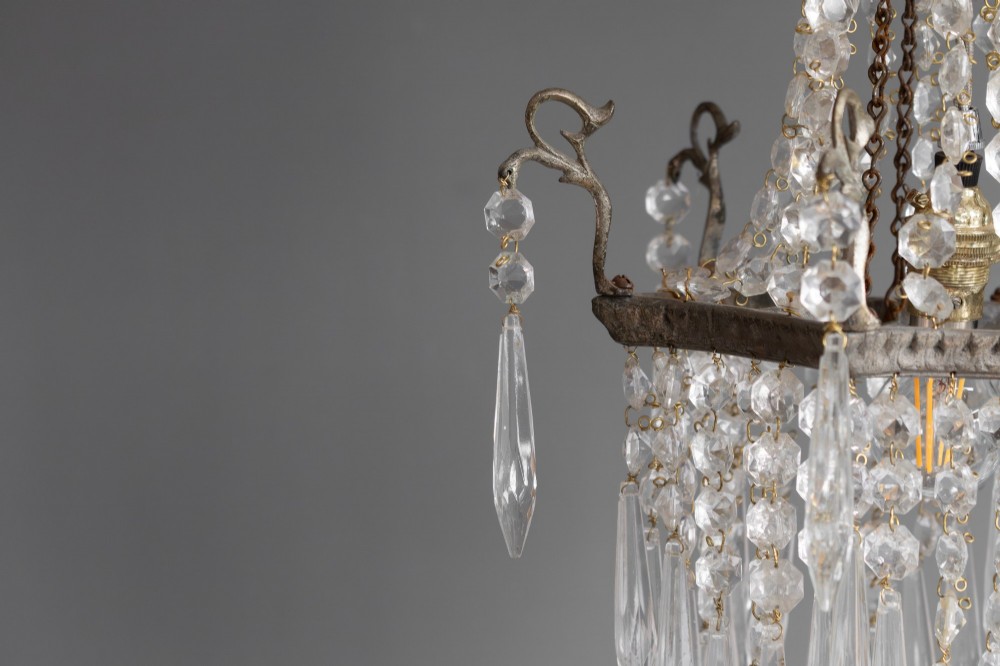 An antique French style crystal chandelier featuring tiered glass prisms, beaded crystal strands, and a decorative aged brass frame. View VI