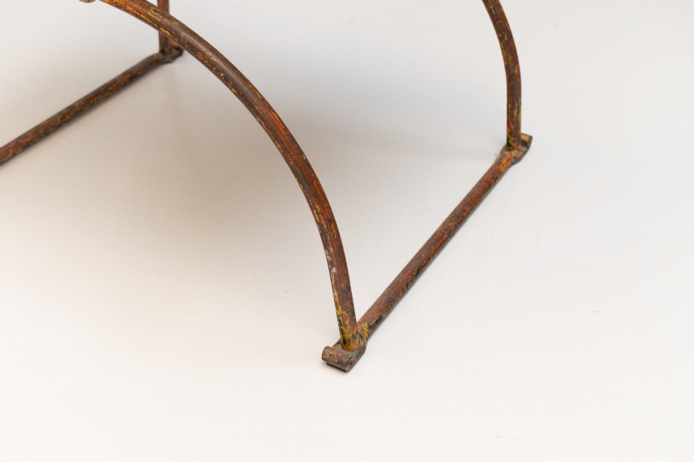A pair of wrought iron X-frame curule side chairs featuring scrolled metal finials and stretched tan hide sling seats. View VIII