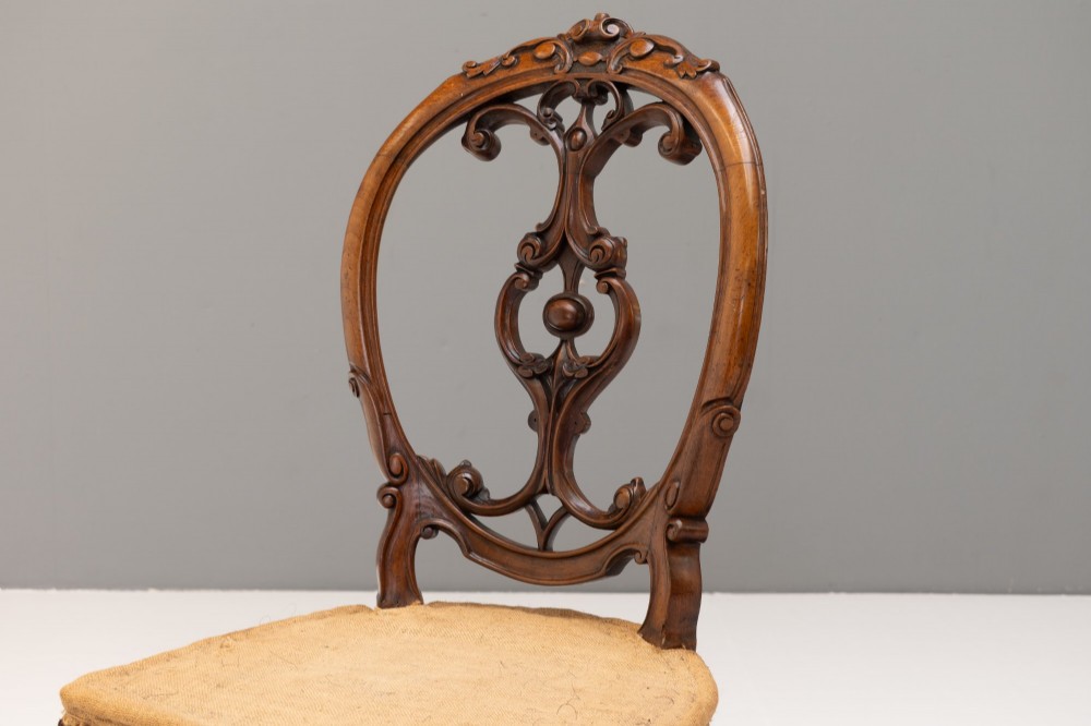 A pair of antique Victorian Rococo Revival carved timber side chairs with balloon backs, open scrollwork splats, cabriole legs, and neutral upholstery. View IV